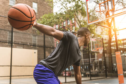 Afro-amerikanischer Basketballspieler beim Training auf einem Platz in New York - Sportlicher Mann beim Basketballspielen im Freien - DMDF02003