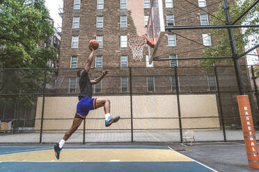 Afro-american basketball player training on a court in New York - Sportive man playing basket outdoors - DMDF02004