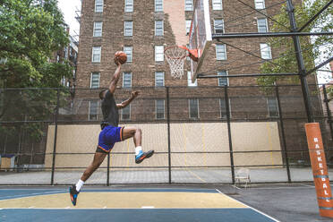 Afro-amerikanischer Basketballspieler beim Training auf einem Platz in New York - Sportlicher Mann beim Basketballspielen im Freien - DMDF02004