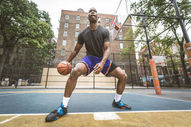 Afro-american basketball player training on a court in New York - Sportive man playing basket outdoors - DMDF02008