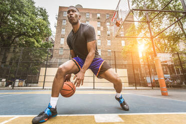 Afro-american basketball player training on a court in New York - Sportive man playing basket outdoors - DMDF02009