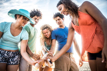 Multicultural group of friends partying on the beach - Young people celebrating during summer vacation, summertime and holidays concepts - DMDF02017