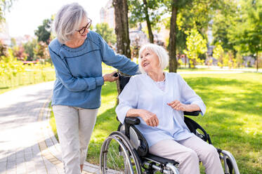 Beautiful senior women with disability outdoors - Old people in the age of 60, 70, 80 having fun and spending time together, concepts about elderly, seniority, healthcare and wellness aging - DMDF02121