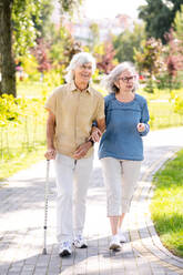 Beautiful senior couple with disability outdoors - Old people in the age of 60, 70, 80 having fun and spending time together, concepts about elderly, seniority, healthcare and wellness aging - DMDF02122