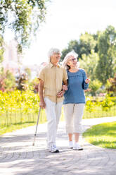 Beautiful senior couple with disability outdoors - Old people in the age of 60, 70, 80 having fun and spending time together, concepts about elderly, seniority, healthcare and wellness aging - DMDF02124
