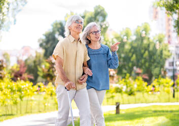 Beautiful senior couple with disability outdoors - Old people in the age of 60, 70, 80 having fun and spending time together, concepts about elderly, seniority, healthcare and wellness aging - DMDF02125