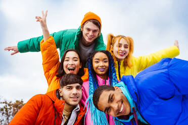 Multiracial group of young happy friends meeting outdoors in winter, wearing winter jackets and having fun - Multiethnic millennials bonding in a urban area, concepts about youth and social releationships - DMDF02130