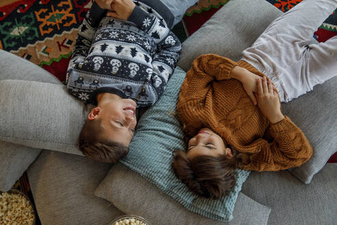 Happy siblings lying on pillows at home - IKF01098