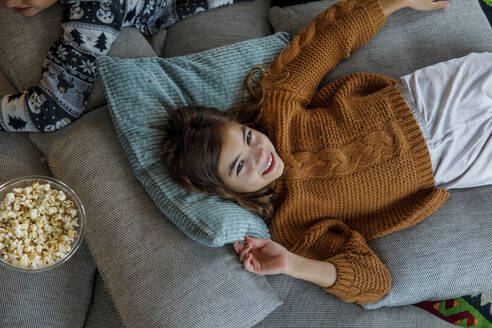 Happy girl relaxing on pillows by brother at home - IKF01105