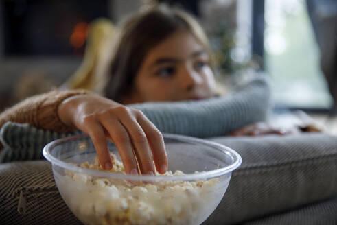 Girl having popcorn from bowl at home - IKF01108