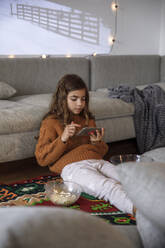 Mädchen benutzt Smartphone im Wohnzimmer - IKF01117