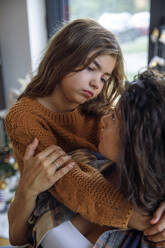 Besorgtes Mädchen umarmt Mutter zu Hause - IKF01133