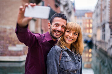 Beatiful young couple having fun while visiting Venice - Tourists travelling in Italy and sightseeing the most relevant landmarks of Venezia - Concepts about lifestyle, travel, tourism - DMDF02172