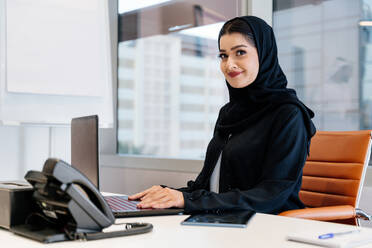 Middle-eastern businesswoman wearing traditional arab abaya working in the office in Dubai - Adult arabian corporate business woman working in the UAE - DMDF02246