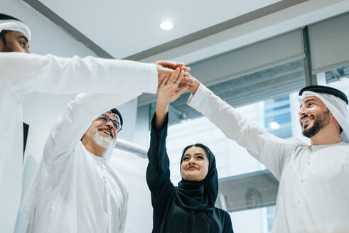 Group of middle-eastern corporate business people wearing traditional emirati clothes meeting in the office in Dubai - Business team working and brainstorming in the UAE - DMDF02251