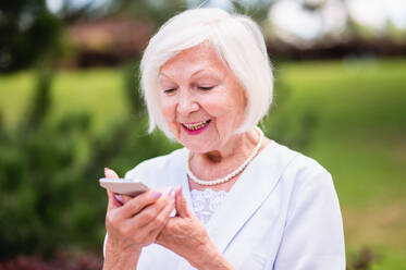 Schöne ältere alte Frau mit silbernem Haar Porträt im Freien - Ältere weibliche Erwachsene mit modernen Kommunikationstechnologie Gerät - DMDF02299