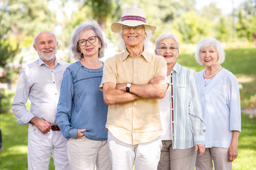 Group of happy elderly people bonding outdoors at the park - Old people in the age of 60, 70, 80 having fun and spending time together, concepts about elderly, seniority and wellness aging - DMDF02304