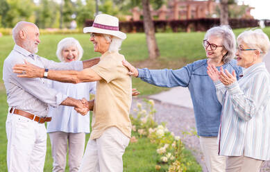 Gruppe glücklicher älterer Menschen, die sich im Freien im Park treffen - Alte Menschen im Alter von 60, 70, 80 Jahren, die Spaß haben und Zeit miteinander verbringen, Konzepte über ältere Menschen, Seniorität und Wellness im Alter - DMDF02312