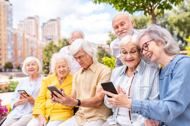 Gruppe glücklicher älterer Menschen, die sich im Freien im Park treffen - Alte Menschen im Alter von 60, 70, 80 Jahren, die Spaß haben und Zeit miteinander verbringen, Konzepte über ältere Menschen, Seniorität und Wellness im Alter - DMDF02322
