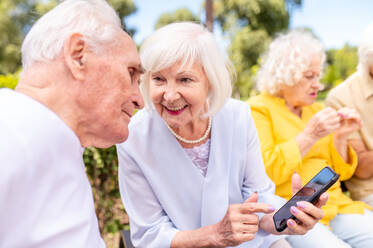 Gruppe glücklicher älterer Menschen, die sich im Freien im Park treffen - Alte Menschen im Alter von 60, 70, 80 Jahren, die Spaß haben und Zeit miteinander verbringen, Konzepte über ältere Menschen, Seniorität und Wellness im Alter - DMDF02325