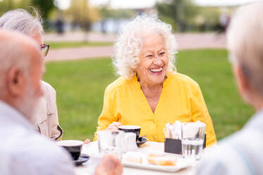 Gruppe glücklicher älterer Menschen, die sich im Freien in der Bar-Cafeteria treffen - Alte Menschen im Alter von 60, 70, 80 Jahren, die Spaß haben und Zeit miteinander verbringen, Konzepte über ältere Menschen, Seniorität und Wellness-Aging - DMDF02348