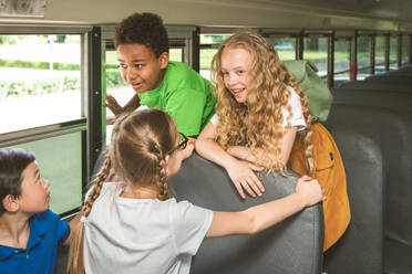 Group of young students attending primary school on a yellow school bus - Elementary school kids ha1ving fun - DMDF02356