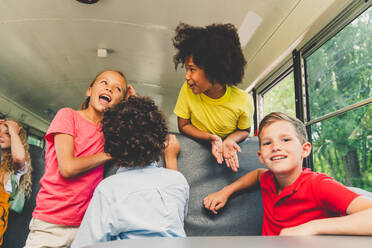 Group of young students attending primary school on a yellow school bus - Elementary school kids ha1ving fun - DMDF02357