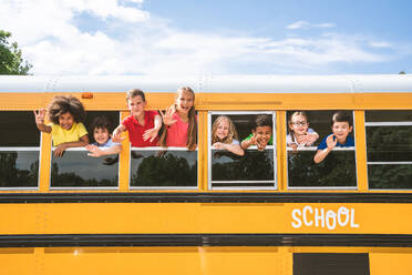 Group of young students attending primary school on a yellow school bus - Elementary school kids ha1ving fun - DMDF02360