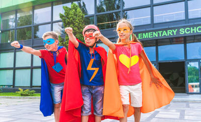 Eine gemischtrassige Gruppe junger Schüler trägt Superheldenkostüme und hat Spaß im Freien - DMDF02369