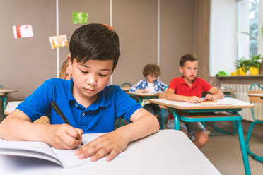 Multiracial group of kids at primary school - Playful schoolers enjoying school time and lesson with teacher and classmates - DMDF02378