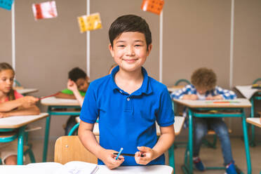 Gemischtrassige Gruppe von Kindern in der Grundschule - Verspielte Schüler genießen die Schulzeit und den Unterricht mit Lehrern und Mitschülern - DMDF02385