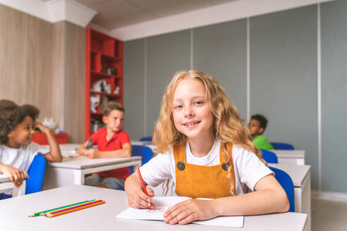 Gemischtrassige Gruppe von Kindern in der Grundschule - Verspielte Schüler genießen die Schulzeit und den Unterricht mit Lehrern und Mitschülern - DMDF02390