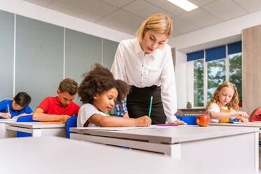 Multiracial group of kids at primary school - Playful schoolers enjoying school time and lesson with teacher and classmates - DMDF02391