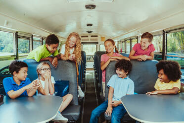 Group of young students attending primary school on a yellow school bus - Elementary school kids ha1ving fun - DMDF02393