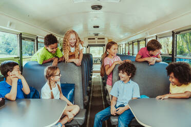 Group of young students attending primary school on a yellow school bus - Elementary school kids ha1ving fun - DMDF02394