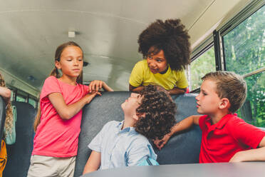 Group of young students attending primary school on a yellow school bus - Elementary school kids ha1ving fun - DMDF02396