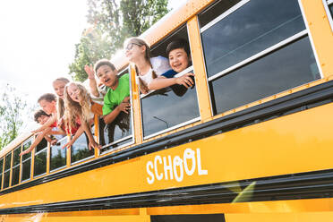 Group of young students attending primary school on a yellow school bus - Elementary school kids ha1ving fun - DMDF02399