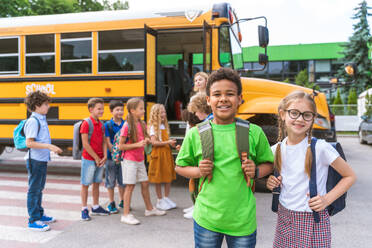 Group of young students attending primary school on a yellow school bus - Elementary school kids ha1ving fun - DMDF02412