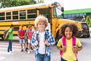 Group of young students attending primary school on a yellow school bus - Elementary school kids ha1ving fun - DMDF02414