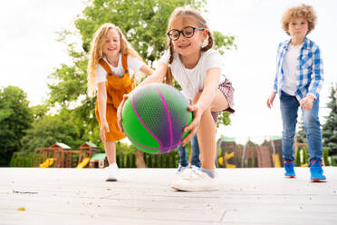 Multiracial group of kids playing at playground during break - Playful primary school students having fun - DMDF02418