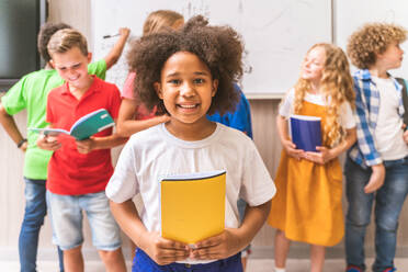 Gemischtrassige Gruppe von Kindern in der Grundschule - Verspielte Schüler genießen die Schulzeit und den Unterricht mit Lehrern und Mitschülern - DMDF02426