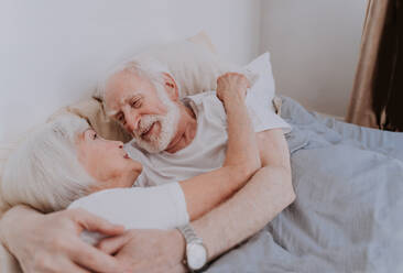 Beautiful senior couple enjoying time together at home - Romantic moments at home, elderly couple in bed at home - DMDF02444