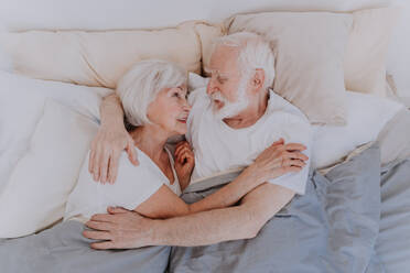 Beautiful senior couple enjoying time together at home - Romantic moments at home, elderly couple in bed at home - DMDF02447