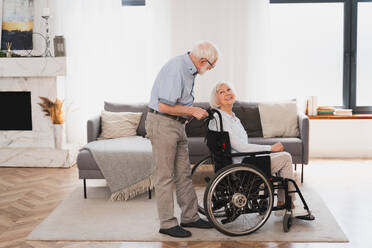 Disabled old woman on wheel chair - Senior couple at home, partner coming back from hospital in convalescence - DMDF02455