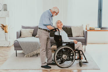 Disabled old man on wheel chair - Senior couple at home, partner coming back from hospital in convalescence - DMDF02458