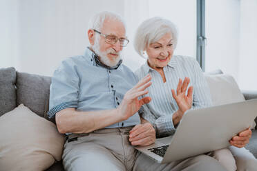 Älteres Paar kauft online im Internet mit Computer Laptop zu Hause - Schöne glückliche ältere Menschen mit PC und sozialen Netzwerk-Apps - DMDF02474