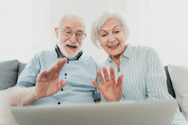 Älteres Paar kauft online im Internet mit Computer Laptop zu Hause - Schöne glückliche ältere Menschen mit PC und sozialen Netzwerk-Apps - DMDF02475