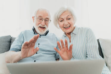 Elderly couple shopping online on internet with computer laptop at home - Beautiful happy senior people using pc and social network apps - DMDF02475