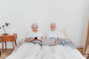 Schönes älteres Paar genießt die gemeinsame Zeit zu Hause - Moderates älteres Paar surft im Internet auf einem Laptop-Computer - DMDF02497