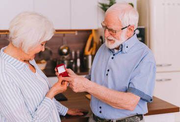 Senior couple wedding proposal, - Elderly man asking his woman to marry him, engagement ring gift - DMDF02522